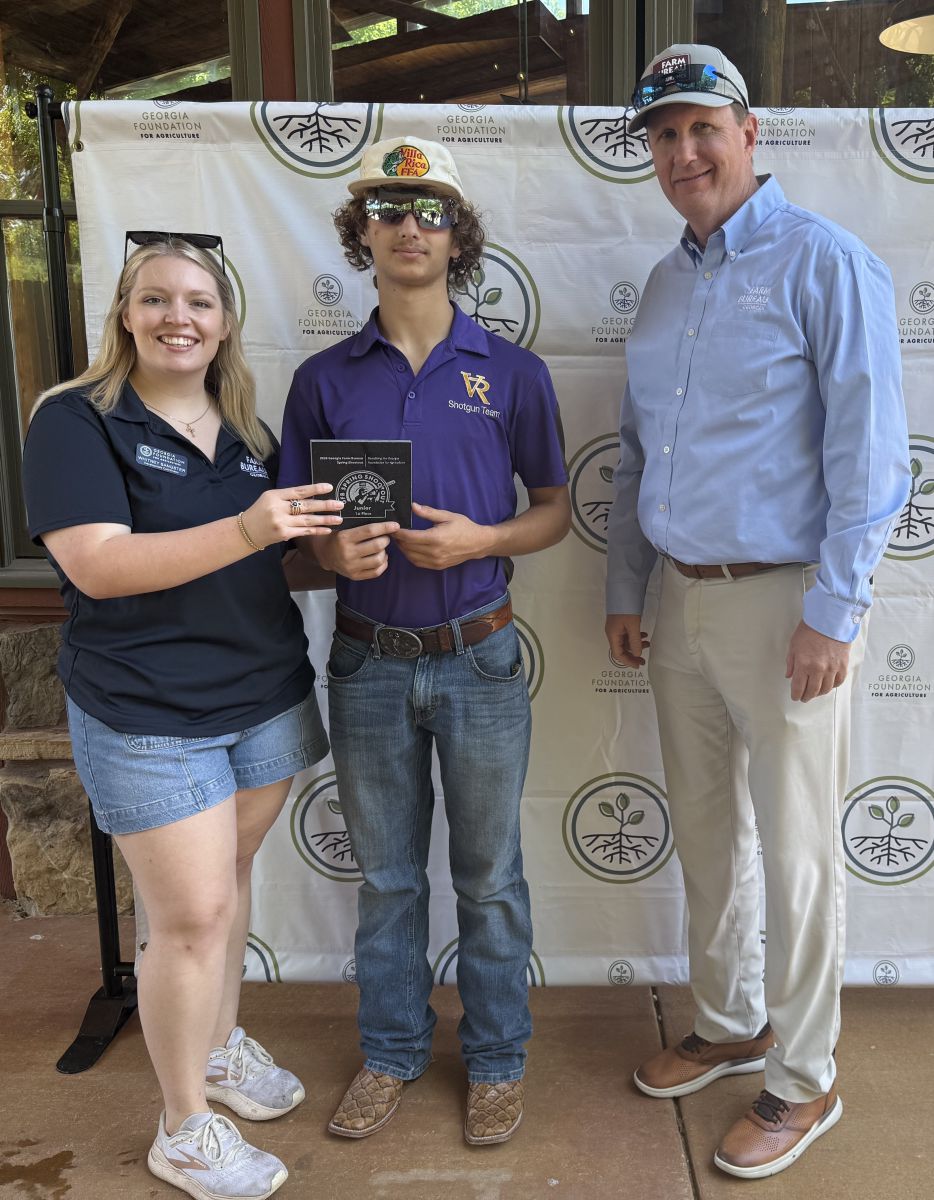 teenage boy in center accepts small granite plaque from young lady on left side while tall man offers congratulations.