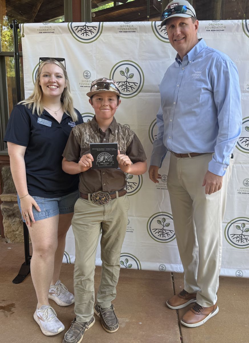 young boy, standing center, accepts small granite plaque from young lady on left and tall man on right