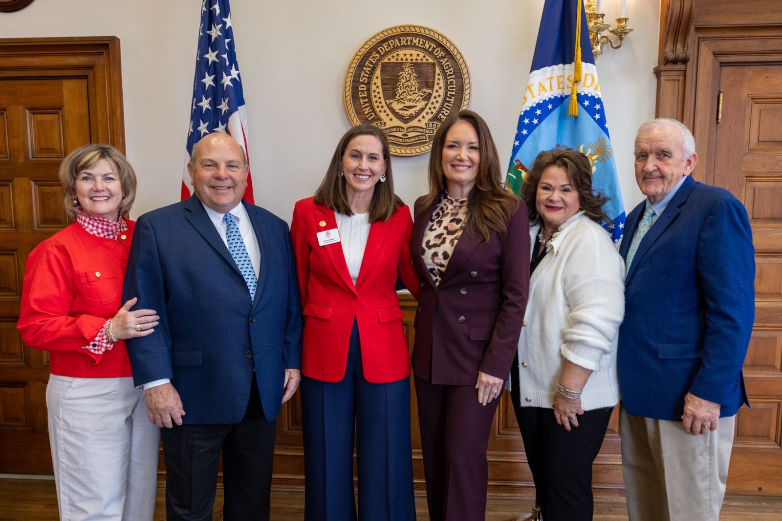 A group of six people posing in front of U.S. and USDA flags.