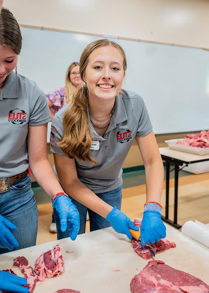 A teen-aged girl cutting raw meat.