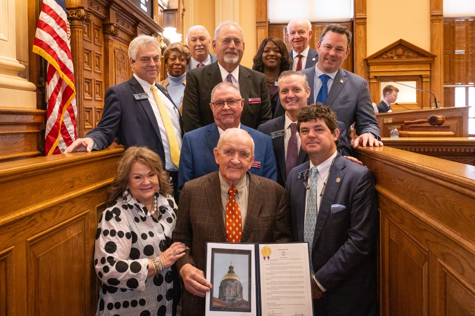 Group of 12 men and women standing in Georgia Senate. Eight senate leaders are presenting a proclamation to Georgia Farm Bureau leaders.