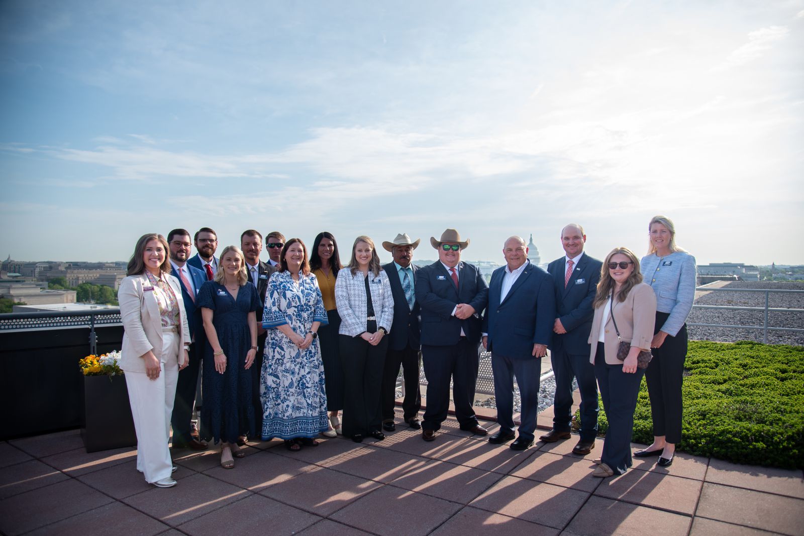 A group of 15 people dressed in business dress on top of a building.