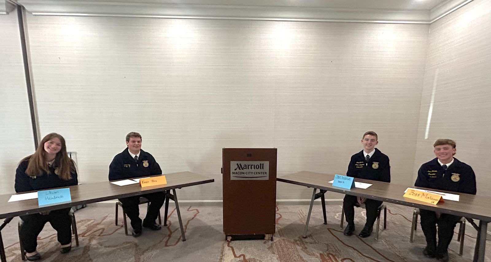 Four students seated at tables during discussion meet.