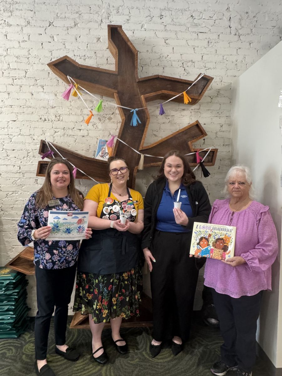 A group of four women holding farm-related media and classroom projects.