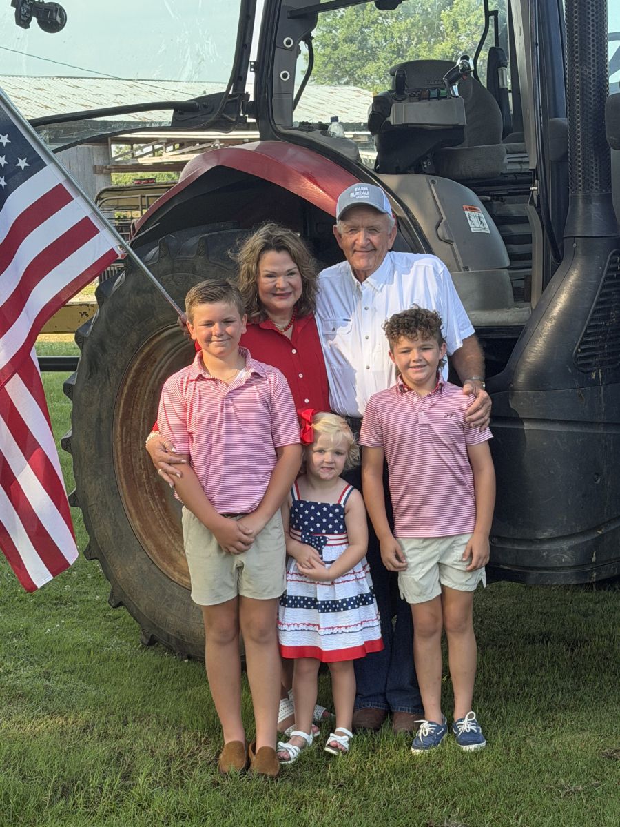 Photo of Tom and Jane McCall with GFB President Tom McCall with grandchildren Winn, McCall, and Wilkes in front of a tractor with the American flag. /photo courtesy of the McCall family