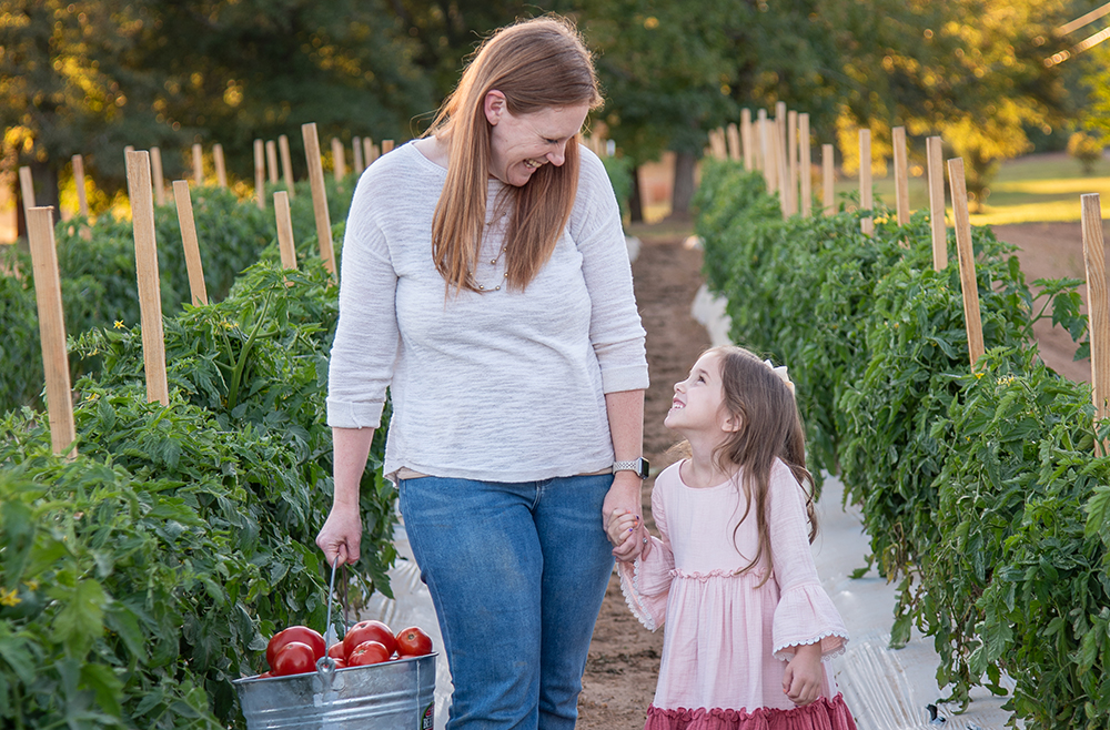 mom and daughter walking through tomato crop